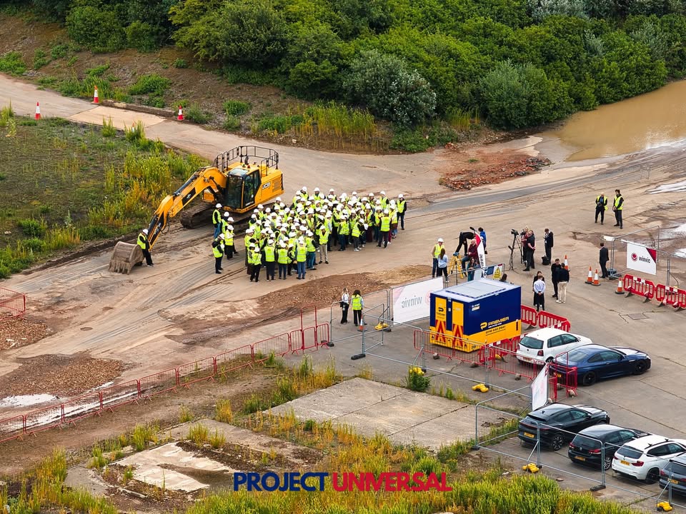 Hi-vis crowd, a JCB and Sky News cameras at the Universal site