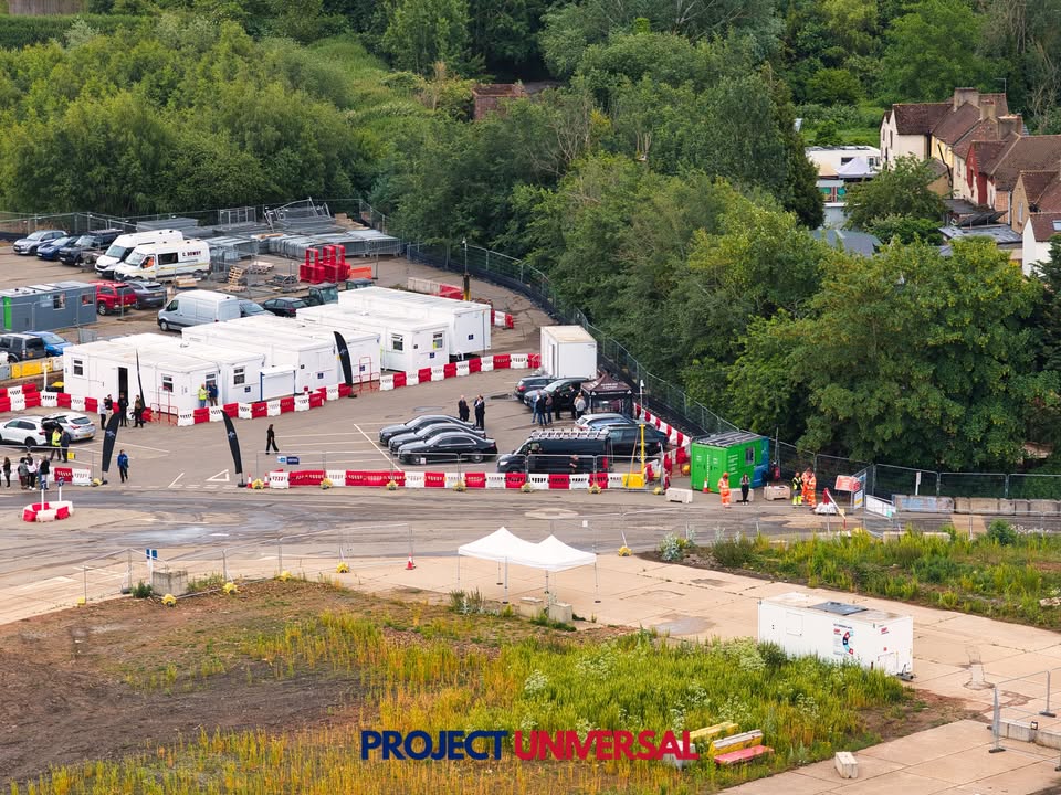 Hi-vis crowd, a JCB and Sky News cameras at the Universal site