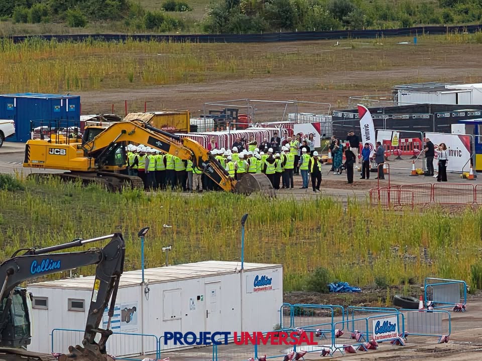 Hi-vis crowd, a JCB and Sky News cameras at the Universal site