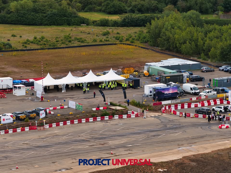 Hi-vis crowd, a JCB and Sky News cameras at the Universal site